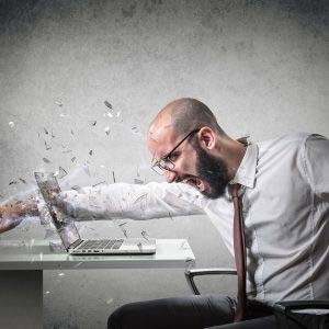 Frustrated man punching laptop screen