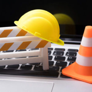 Road Barrier With Hard Hat And Traffic Cone On Laptop Keypad