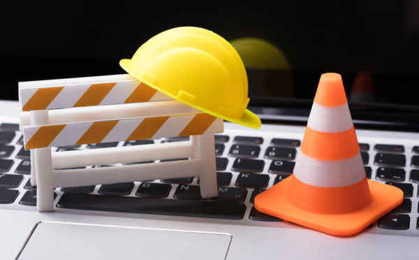Road Barrier With Hard Hat And Traffic Cone On Laptop Keypad