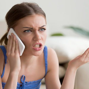 Angry young woman arguing talking on phone at home